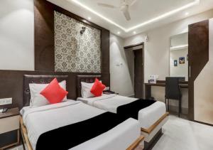 2 camas en una habitación de hotel con almohadas rojas en The Ganga Residency, en Bārh