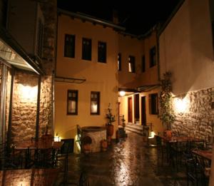 un patio vacío con mesas y sillas por la noche en Hagiati Guesthouse, en Ioannina