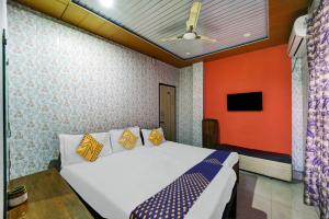 OYO Hotel USA Hotel في سيلكار: غرفة نوم بسرير ابيض وجدار برتقالي