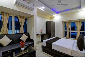 een slaapkamer met een bed, een bank en ramen bij Townhouse Hotel Refresh in Calcutta