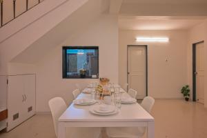 een witte eetkamer met een witte tafel en stoelen bij Bellezza By Stayscape Villas in Kārli