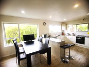 una cucina con tavolo e sedie e una cucina con bancone di Sunshine hillcrest home ad Auckland