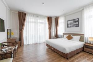 a bedroom with a large white bed and a desk at PINE VIEW Hotel Dalat in Da Lat