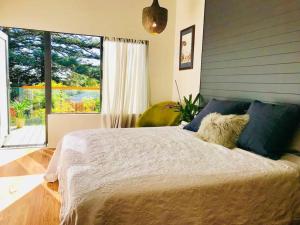 a bedroom with a bed and a large window at Tree Top Rest - Bright Water Retreat in Bundeena