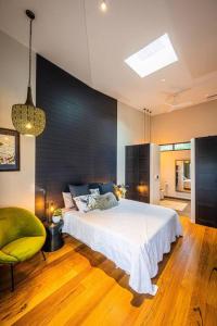 a bedroom with a large bed and a chair at Tree Top Rest - Bright Water Retreat in Bundeena