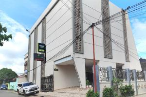 un edificio blanco con un coche aparcado fuera de él en Urbanview Hotel Syariah near Polda Jambi, en Palmerah