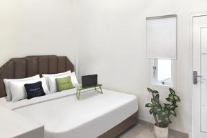 a white bedroom with a bed with a laptop on it at Urbanview Hotel Syariah near Polda Jambi in Paalmerah