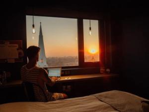 a man sitting at a desk with a laptop looking out a window at Hotel G Yangon in Yangon