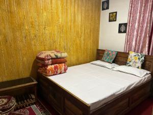 uma pequena cama num quarto com paredes de madeira em Kunsang Homestay em Ghum