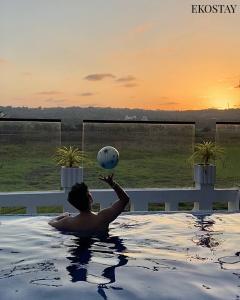 EKOSTAY Luxe - Jade Villa I Infinity Pool I Paddy Field Views في كاندوليم: رجل في حوض الاستحمام يمسك الكرة