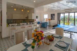eine Küche und ein Wohnzimmer mit einem Tisch mit Blumen darauf in der Unterkunft EKOSTAY Luxe - Jade Villa I Infinity Pool I Paddy Field Views in Candolim