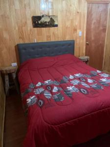 uma cama vermelha com um edredão vermelho em cima em Butamacho Cabaña con Tinaja x Día em Chonchi
