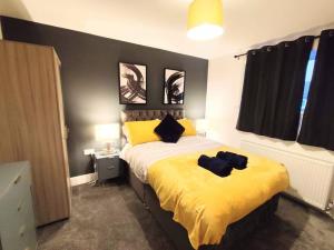 a bedroom with a bed with yellow sheets and black pillows at Sigma Lux Home in Cramlington