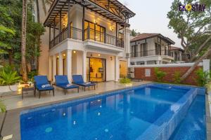 a house with a swimming pool in front of a house at EKOSTAY Luxe - Jade Villa I Infinity Pool I Paddy Field Views in Candolim