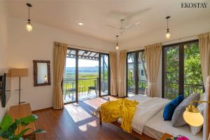 1 dormitorio con 1 cama grande y balcón en EKOSTAY Luxe - Jade Villa I Infinity Pool I Paddy Field Views en Candolim