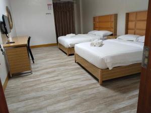 a bedroom with two beds and a desk with a television at Meaco Royal Hotel - Valenzuela in Subusub +10 photos