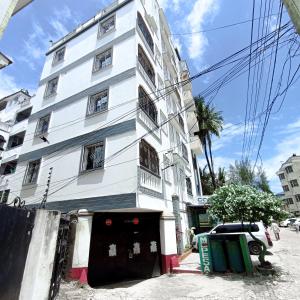 un edificio bianco su una strada con una macchina davanti di Seaside Heights 2BR 43' Smart TV a Mombasa