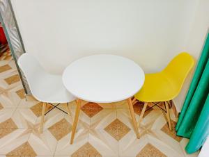 a white table and two yellow chairs in a room at Seaside Heights 2BR 43' Smart TV in Mombasa