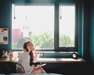 a girl sitting on a chair in front of a window at Hotel G Yangon in Yangon