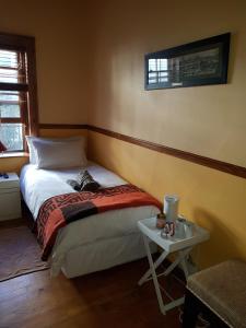 a small bedroom with a bed and a table at Uniondale Guest Lodge in Uniondale