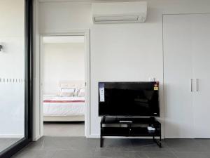 sala de estar con TV y dormitorio en Modern 2Brs@ close2 Olympic park en Sídney