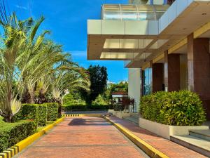 a building with palm trees and a sidewalk at Relaxing 1BR Suite in La Mirada in Mactan