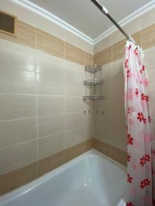 a bath tub with a shower curtain in a bathroom at Кабанбай ЦГБ больница in Semey