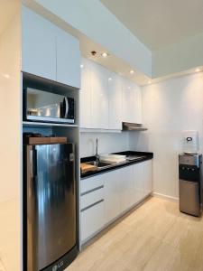 a kitchen with white cabinets and a stainless steel refrigerator at Relaxing 1BR Suite in La Mirada in Mactan