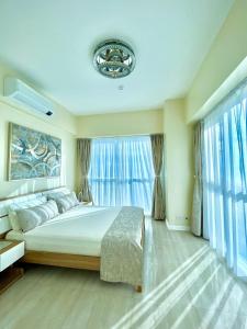 a bedroom with a large bed and large windows at Relaxing 1BR Suite in La Mirada in Mactan