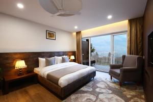 um quarto com uma cama, uma cadeira e uma janela em Kaizen X Voyage Resort And Spa em Manali