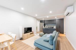 a living room with a blue couch and a kitchen at Convenient Located 2 bedroom apartment in Braddon in Canberra