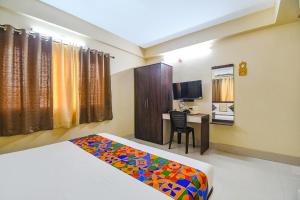 a bedroom with a bed and a desk with a computer at FabHotel New Annapurna Plaza in Pātipukur