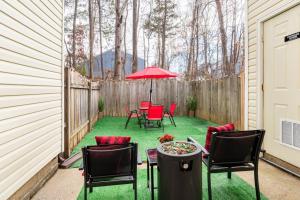 Un patio con sillas y una mesa con sombrilla. en Escape the City w/King Bed, Arcade Games & Firepit, en Norcross