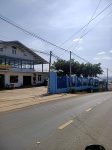 an empty street with a blue fence and a building at TIGOLD Homestay DALAT INN in Da Lat