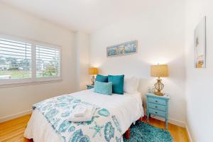 a bedroom with a bed with a blue nightstand and a window at Coastal Bliss in Half Moon Bay