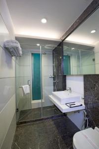 a bathroom with a sink and a shower and a toilet at Jasmine Boutique Hotel Jasola in New Delhi