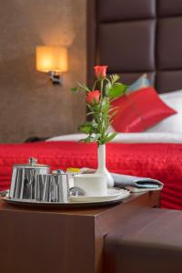 ein Tablett mit einer Vase mit Rosen auf einem Tisch in einem Hotelzimmer in der Unterkunft Jasmine Boutique Hotel Jasola in Neu-Delhi