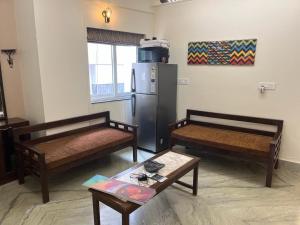 a living room with two beds and a refrigerator at The Broome Kolkata in Kolkata