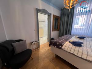ein Schlafzimmer mit einem Bett, einem Stuhl und einem Fenster in der Unterkunft Pension Marie Luise 251 - Zimmer Herzmuschel in Juist