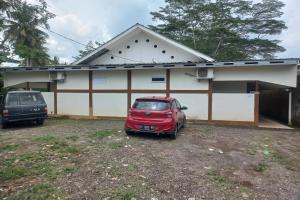 un pequeño coche rojo estacionado frente a una casa en SPOT ON 93557 Juan Kostel 2 en Purwokerto