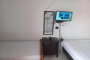 ein Schlafzimmer mit einem Bett und einem TV an der Wand in der Unterkunft SPOT ON 93557 Juan Kostel 2 in Purwokerto