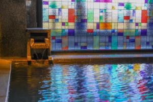 a colorful tile wall next to a pool of water at 別所温泉 七草の湯 in Ueda