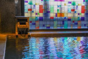 una pared de azulejos de colores junto a una piscina de agua en 別所温泉 七草の湯, en Ueda