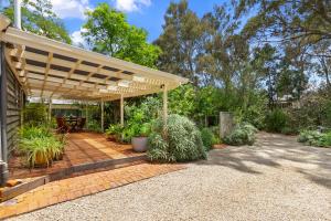 a patio under a wooden pergola with plants at Miriams Cottage in Tanunda