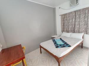 Cette petite chambre comprend un lit et une table. dans l'établissement Mandurah's Inn, Malapascua, à Malapascua