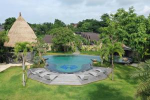 an overhead view of a swimming pool with chairs and a thatch roof at Lalasa Villas Canggu in Canggu