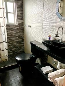 baño con aseo negro y lavamanos en Hidden house, en Ciudad de México