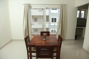 une table à manger avec des chaises et une grande fenêtre dans l'établissement Mee Homes - Madhapur Fully Furnished 2 BHK Flats, à Hyderabad