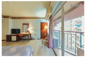 溫泉村的住宿－知本富爺飯店Chihpen Fuye Hotel，一间带一张床和一张书桌的卧室以及一个阳台