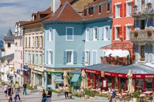 Un groupe de personnes marchant dans une rue avec des bâtiments dans l'établissement Le Cachat - hyper centre - wifi gratuit, à Évian-les-Bains